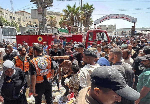 تجمّع فلسطينيون في موقع غارة جوية إسرائيلية قرب مدخل مستشفى شهداء الأقصى في دير البلح، وسط قطاع غزة، بينما كانت فرق الإسعاف تُجلي الجرحى من الموقع، في 25 يوليو/تموز 2026.صورة: أحمد إبراهيم