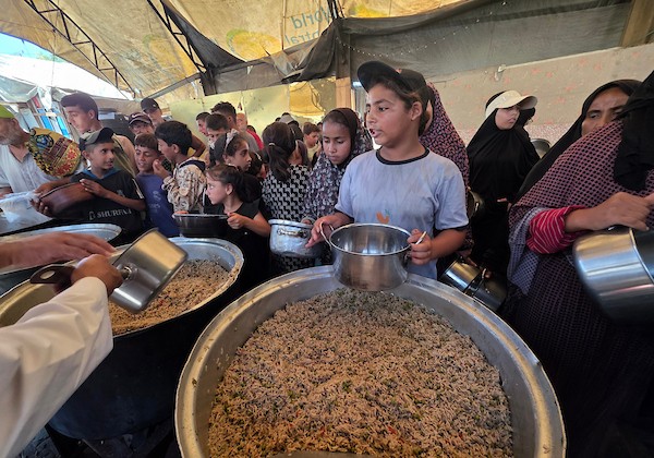 فلسطينيون نازحون يتلقون وجبات طعام مطبوخة من مطبخ خيري محلي في منطقة المواصي غربي خان يونس، جنوبي قطاع غزة، في 10 يوليو/تموز 2026. تصوير: طارق محمد