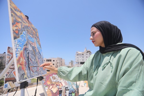 الفنانة جانا محمود أبو هربيد، 21 عامًا، ترسم على سطح منزل عائلتها المتضرر بعد عودتها إلى شمال قطاع غزة، في 20 يوليو/تموز 2026.تصوير: بلال أسامة