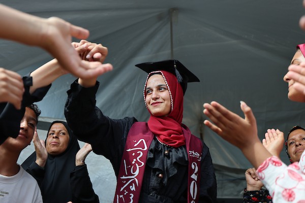الطالبة دانا سعادة تحتفل مع عائلتها داخل خيمة للنازحين غرب مدينة غزة، بعد حصولها على معدل 96% في الفرع الأدبي بامتحانات التوجيهي، 24 تموز/ يوليو 2026. تصوير: بلال أسامة