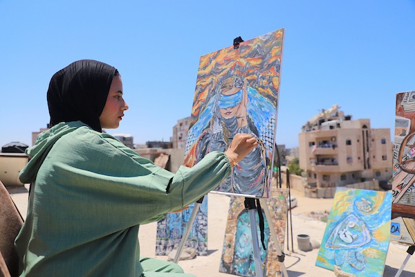 الفنانة جانا محمود أبو هربيد، 21 عامًا، ترسم على سطح منزل عائلتها المتضرر بعد عودتها إلى شمال قطاع غزة، في 20 يوليو/تموز 2026.تصوير: بلال أسامة