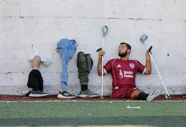 مبتورو الأطراف في غزة يعودون إلى الملعب برسالة صمود واندماج  شارك لاعبون فلسطينيون من مبتوري الأطراف، أصيبوا خلال الحرب في قطاع غزة، في مباراة رمزية أُقيمت على ملعب فلسطين بمدينة غزة، يوم 28 يوليو/تموز 2026، في مبادرة جمعت بين الرياضة والدعم الإنساني.  ونُظمت المباراة بالتعاون مع مؤسسة «دنيز فنيري»، بهدف دعم الرياضيين من مبتوري الأطراف وتعزيز دمج الأشخاص ذوي الإعاقة في المجتمع من خلال الرياضة، في ظل الظروف الصعبة التي يعيشها سكان القطاع.  وحملت عودة اللاعبين إلى أرض الملعب دلالة تتجاوز المنافسة الرياضية، إذ عكست تمسكهم بالحياة وقدرتهم على تجاوز آثار الإصابة واستعادة مساحة من النشاط والأمل، رغم التحديات الجسدية والنفسية التي خلّفتها الحرب.  وسعت المبادرة إلى تسليط الضوء على احتياجات المصابين من ذوي الإعاقة، وفتح المجال أمامهم لمواصلة ممارسة الرياضة والمشاركة الفاعلة في المجتمع.  تعليق الصورة: لاعبون فلسطينيون من مبتوري الأطراف يشاركون في مباراة رمزية على ملعب فلسطين بمدينة غزة، 28 يوليو/تموز 2026. تصوير: بلال أسامة.
