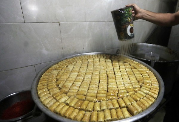 عمال يُعدّون تشكيلة من الحلويات داخل محل في مدينة غزة، في 23 يوليو/تموز 2026، عشية إعلان نتائج امتحان «التوجيهي». تصوير: بلال أسامة