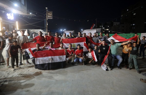 فلسطينيون يتابعون عبر شاشة عرض عامة في مدينة غزة مباراة مصر وأستراليا ضمن دور الـ32 من كأس العالم، في 3 يوليو/تموز 2026، وسط التحديات الإنسانية المستمرة في القطاع.  صورة: بلال أسامة