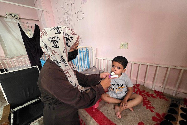 الفلسطينية إيمان أبو جامع تجلس إلى جانب طفلها ياسر عرفات، البالغ ست سنوات، أثناء تلقيه العلاج من سوء التغذية في مجمع ناصر الطبي بخان يونس، جنوب قطاع غزة، في 8 يوليو/تموز 2026. وتقول الأم إنها فقدت زوجها وابنًا آخر بسبب مضاعفات سوء التغذية. تصوير: طارق محمد