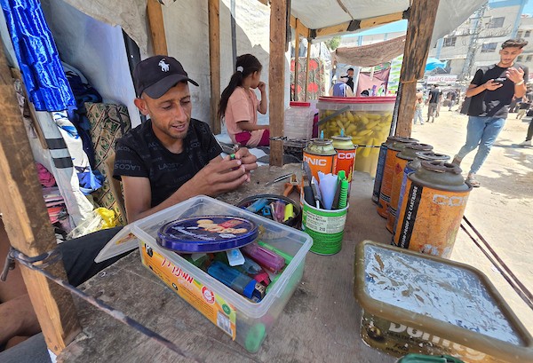 عامل فلسطيني يصلح ولاعات غاز مستعملة داخل ورشة في خان يونس، جنوب قطاع غزة، في 28 يوليو/تموز 2026. تصوير: طارق محمد.