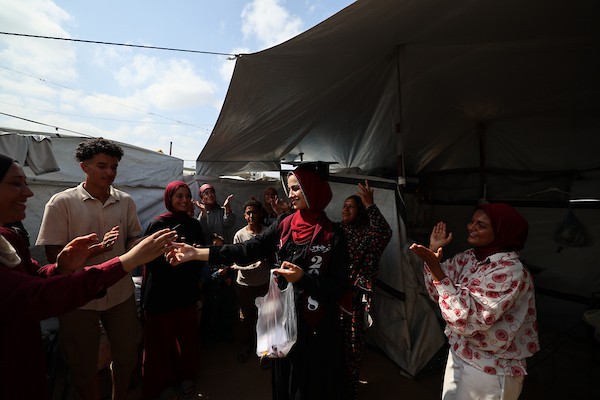 الطالبة دانا سعادة تحتفل مع عائلتها داخل خيمة للنازحين غرب مدينة غزة، بعد حصولها على معدل 96% في الفرع الأدبي بامتحانات التوجيهي، 24 تموز/ يوليو 2026. تصوير: بلال أسامة
