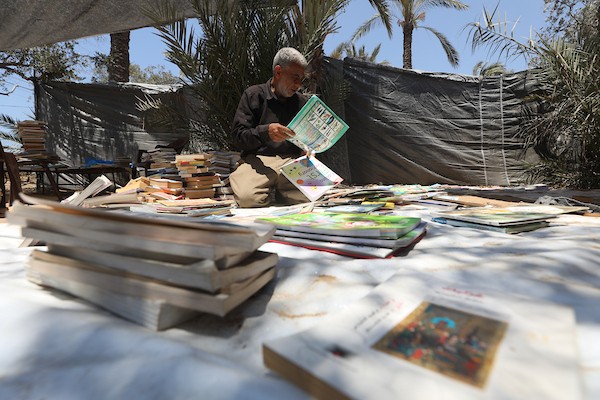 يعرض بائع الكتب محمد رمضان سعد ( 56 عامًا) مجموعة من الكتب في كشك على جانب الطريق في دير البلح، وسط قطاع غزة، في 2 يوليو/تموز 2026. تصوير: حسن الجدي