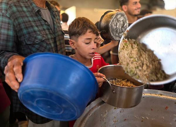 فلسطينيون نازحون يتلقون وجبات طعام مطبوخة من مطبخ خيري محلي في منطقة المواصي غربي خان يونس، جنوبي قطاع غزة، في 10 يوليو/تموز 2026. تصوير: طارق محمد