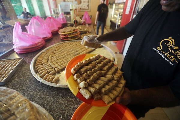عمال يُعدّون تشكيلة من الحلويات داخل محل في مدينة غزة، في 23 يوليو/تموز 2026، عشية إعلان نتائج امتحان «التوجيهي». تصوير: بلال أسامة