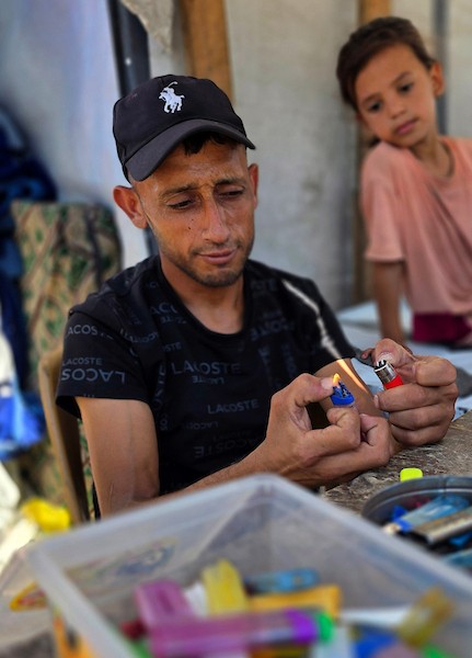 عامل فلسطيني يصلح ولاعات غاز مستعملة داخل ورشة في خان يونس، جنوب قطاع غزة، في 28 يوليو/تموز 2026. تصوير: طارق محمد.