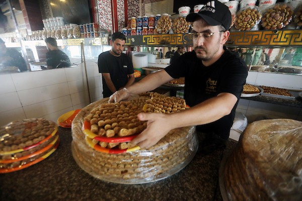 عمال يُعدّون تشكيلة من الحلويات داخل محل في مدينة غزة، في 23 يوليو/تموز 2026، عشية إعلان نتائج امتحان «التوجيهي». تصوير: بلال أسامة