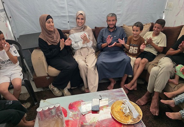 الطالبة نور عودة تحتفل مع عائلتها داخل منزل متضرر في خان يونس، بعد حصولها على معدل 99.7% في المسار العلمي وحلولها أولى على قطاع غزة وثانية على مستوى فلسطين في امتحانات التوجيهي، 24 تموز/ يوليو 2026. تصوير: طارق محمد
