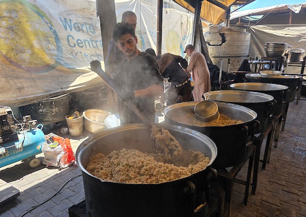 فلسطينيون نازحون يتلقون وجبات طعام مطبوخة من مطبخ خيري محلي في منطقة المواصي غربي خان يونس، جنوبي قطاع غزة، في 10 يوليو/تموز 2026. تصوير: طارق محمد