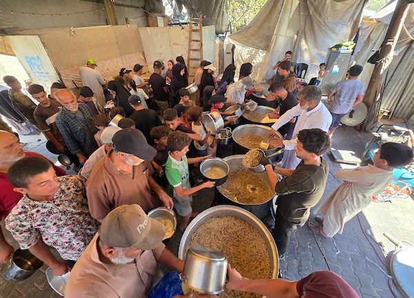 فلسطينيون نازحون يتلقون وجبات طعام مطبوخة من مطبخ خيري محلي في منطقة المواصي غربي خان يونس، جنوبي قطاع غزة، في 10 يوليو/تموز 2026. تصوير: طارق محمد