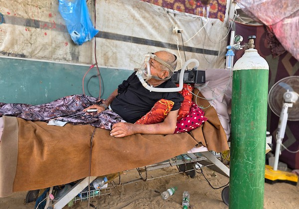 فتحي حجي، 77 عاماً، مريض كلى ويستخدم أسطوانة أكسجين، يجلس على كرسي متحرك أثناء نقله على عربة تجرها الحيوانات من منطقة بئر 19 في المواصي بمدينة خان يونس، جنوب قطاع غزة، في 22 يوليو/تموز 2026.  تصوير: طارق محمد