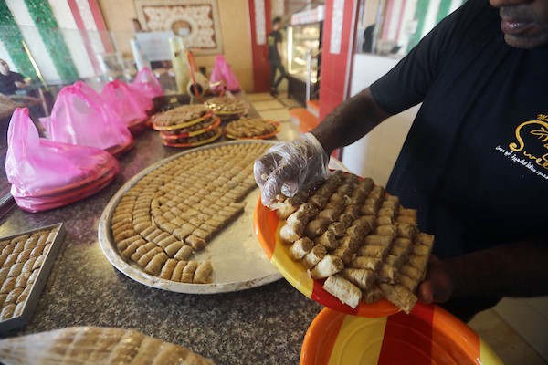 عمال يُعدّون تشكيلة من الحلويات داخل محل في مدينة غزة، في 23 يوليو/تموز 2026، عشية إعلان نتائج امتحان «التوجيهي». تصوير: بلال أسامة
