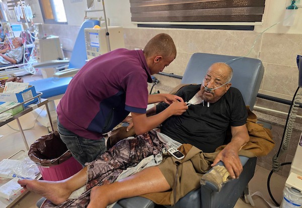 فتحي حجي، 77 عاماً، مريض كلى ويستخدم أسطوانة أكسجين، يجلس على كرسي متحرك أثناء نقله على عربة تجرها الحيوانات من منطقة بئر 19 في المواصي بمدينة خان يونس، جنوب قطاع غزة، في 22 يوليو/تموز 2026.  تصوير: طارق محمد