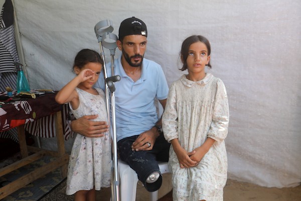 الحلاق الفلسطيني شادي البراوي، 35 عاما، يعمل داخل خيمة نزح إليها مع عائلته في مدينة غزة، في 27 آب/أغسطس 2026، بعدما فقد ساقه اليمنى إثر إصابته بشظايا خلال هجوم إسرائيلي.(تصوير: بلال أسامة)