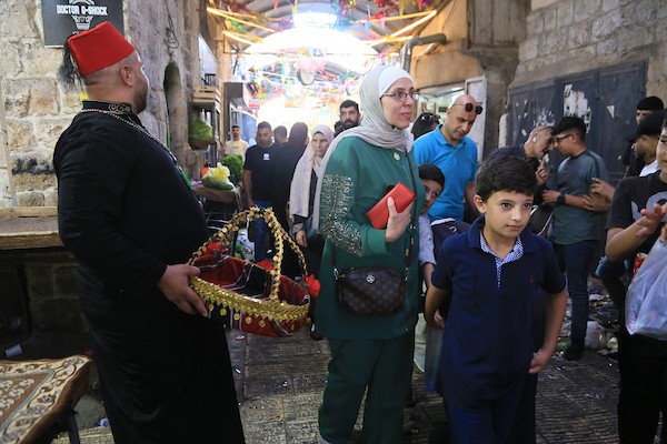 فلسطينيون بالزي التقليدي يؤدون أناشيد ومدائح دينية ويوزعون الحلوى في السوق المركزي بالبلدة القديمة في نابلس،خلال إحياء ذكرى المولد النبوي الشريف، في 25 أغسطس/آب 2026. (تصوير: محمد ناصر)