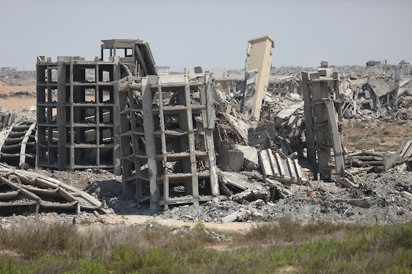 فلسطينيون يتنقلون بين أنقاض مبانٍ مدمرة في منطقة المغاري وسط قطاع غزة، في مشهد يعكس حجم الأضرار التي لحقت بالمناطق السكنية خلال الحرب. (تصوير: حسن الجدي)