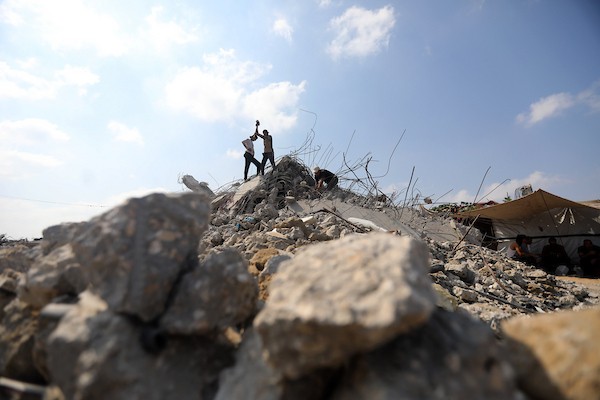 عمال فلسطينيون يستخرجون الحديد من أنقاض منازل مدمرة في حي التفاح بمدينة غزة لإعادة استخدامه في تدعيم خيام ومساكن مؤقتة للنازحين. (تصوير: بلال أسامة)