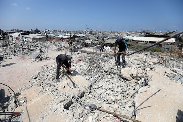 عمال فلسطينيون يستخرجون الحديد من أنقاض منازل مدمرة في حي التفاح بمدينة غزة لإعادة استخدامه في تدعيم خيام ومساكن مؤقتة للنازحين. (تصوير: بلال أسامة)