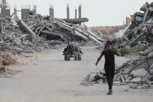 فلسطينيون يتنقلون بين أنقاض مبانٍ مدمرة في منطقة المغاري وسط قطاع غزة، في مشهد يعكس حجم الأضرار التي لحقت بالمناطق السكنية خلال الحرب. (تصوير: حسن الجدي)