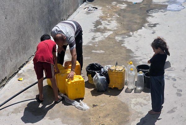 فلسطينيون، بينهم نساء وأطفال، يملؤون حاويات بمياه محلاة في محطة تحلية مياه بخان يونس، جنوب قطاع غزة، في 23 أغسطس/آب 2026.(صورة: طارق محمد)