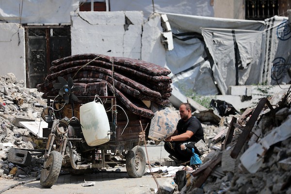 فلسطينيون يسيرون بين أنقاض المباني المدمرة في مخيم جباليا شمال قطاع غزة. تصوير: بلال أسامة