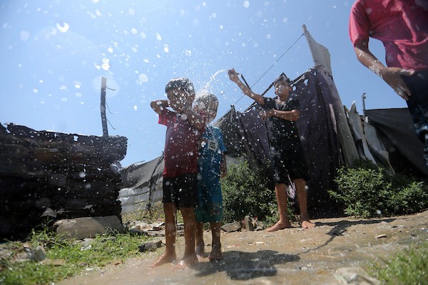 أطفال فلسطينيون نازحون يرتشفون الماء قرب مخيمات النزوح بجوار حي الشجاعية، شرق مدينة غزة، في 9 أغسطس/آب 2026، وسط ارتفاع درجات الحرارة وظروف معيشية صعبة في الخيام ومحدودية وسائل التبريد والخدمات الأساسية. (تصوير: بلال أسامة)