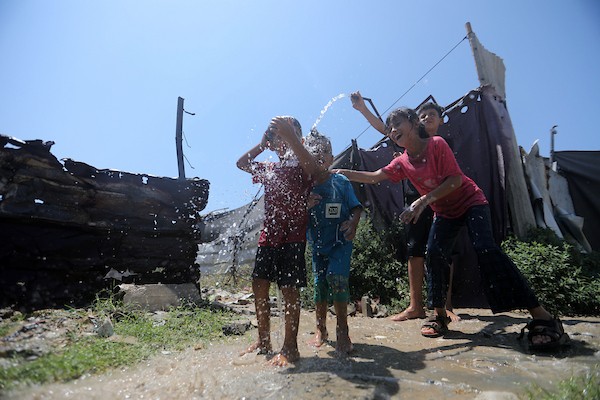 أطفال فلسطينيون نازحون يرتشفون الماء قرب مخيمات النزوح بجوار حي الشجاعية، شرق مدينة غزة، في 9 أغسطس/آب 2026، وسط ارتفاع درجات الحرارة وظروف معيشية صعبة في الخيام ومحدودية وسائل التبريد والخدمات الأساسية. (تصوير: بلال أسامة)