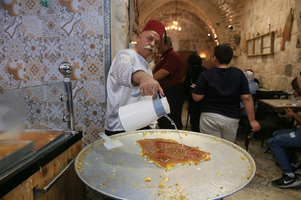 فلسطينيون بالزي التقليدي يؤدون أناشيد ومدائح دينية ويوزعون الحلوى في السوق المركزي بالبلدة القديمة في نابلس،خلال إحياء ذكرى المولد النبوي الشريف، في 25 أغسطس/آب 2026. (تصوير: محمد ناصر)
