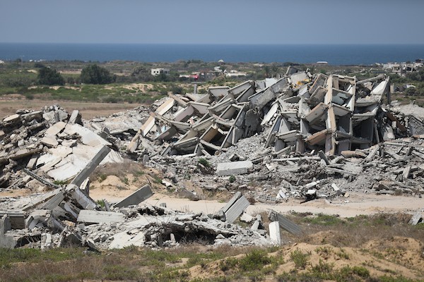 فلسطينيون يتنقلون بين أنقاض مبانٍ مدمرة في منطقة المغاري وسط قطاع غزة، في مشهد يعكس حجم الأضرار التي لحقت بالمناطق السكنية خلال الحرب. (تصوير: حسن الجدي)