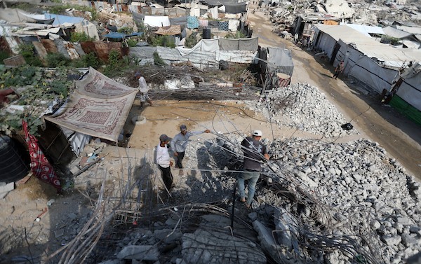 عمال فلسطينيون يستخرجون الحديد من أنقاض منازل مدمرة في حي التفاح بمدينة غزة لإعادة استخدامه في تدعيم خيام ومساكن مؤقتة للنازحين. (تصوير: بلال أسامة)