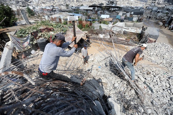 عمال فلسطينيون يستخرجون الحديد من أنقاض منازل مدمرة في حي التفاح بمدينة غزة لإعادة استخدامه في تدعيم خيام ومساكن مؤقتة للنازحين. (تصوير: بلال أسامة)