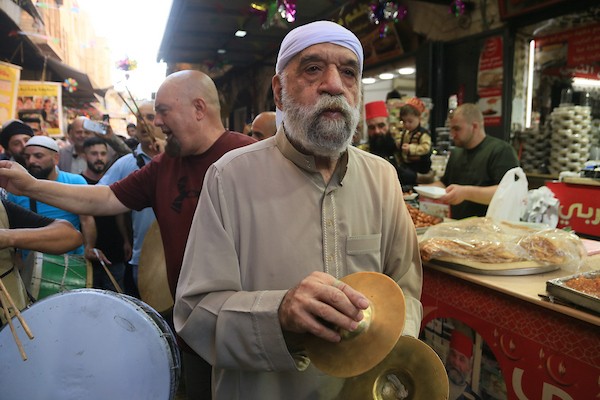 فلسطينيون بالزي التقليدي يؤدون أناشيد ومدائح دينية ويوزعون الحلوى في السوق المركزي بالبلدة القديمة في نابلس،خلال إحياء ذكرى المولد النبوي الشريف، في 25 أغسطس/آب 2026. (تصوير: محمد ناصر)