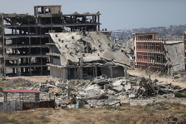 فلسطينيون يتنقلون بين أنقاض مبانٍ مدمرة في منطقة المغاري وسط قطاع غزة، في مشهد يعكس حجم الأضرار التي لحقت بالمناطق السكنية خلال الحرب. (تصوير: حسن الجدي)