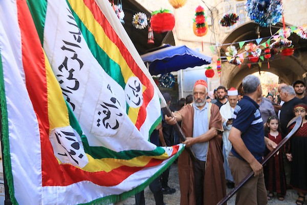 فلسطينيون بالزي التقليدي يؤدون أناشيد ومدائح دينية ويوزعون الحلوى في السوق المركزي بالبلدة القديمة في نابلس،خلال إحياء ذكرى المولد النبوي الشريف، في 25 أغسطس/آب 2026. (تصوير: محمد ناصر)