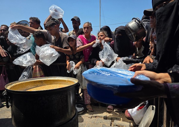 فلسطينيون ينتظرون دورهم للحصول على وجبة من مطبخ خيري في منطقة المواصي بخان يونس، جنوب قطاع غزة، في 7 أغسطس/آب 2026، وسط استمرار الأزمة الإنسانية ونقص الإمدادات الغذائية. تصوير: طارق محمد