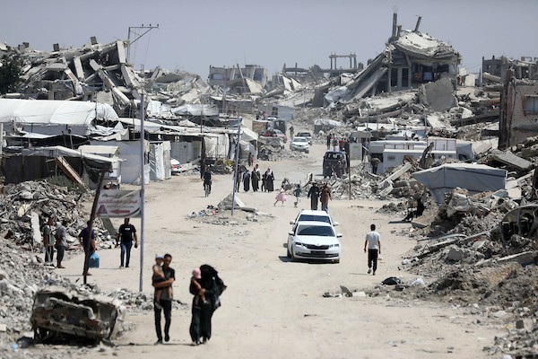 فلسطينيون يسيرون بين أنقاض المباني المدمرة في مخيم جباليا شمال قطاع غزة. تصوير: بلال أسامة