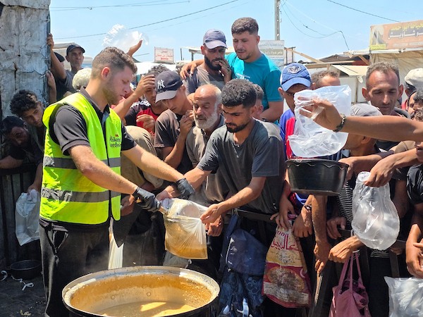 فلسطينيون ينتظرون دورهم للحصول على وجبة من مطبخ خيري في منطقة المواصي بخان يونس، جنوب قطاع غزة، في 7 أغسطس/آب 2026، وسط استمرار الأزمة الإنسانية ونقص الإمدادات الغذائية. تصوير: طارق محمد