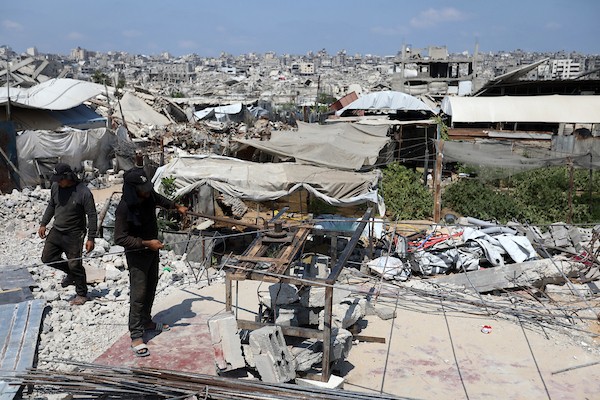 عمال فلسطينيون يستخرجون الحديد من أنقاض منازل مدمرة في حي التفاح بمدينة غزة لإعادة استخدامه في تدعيم خيام ومساكن مؤقتة للنازحين. (تصوير: بلال أسامة)
