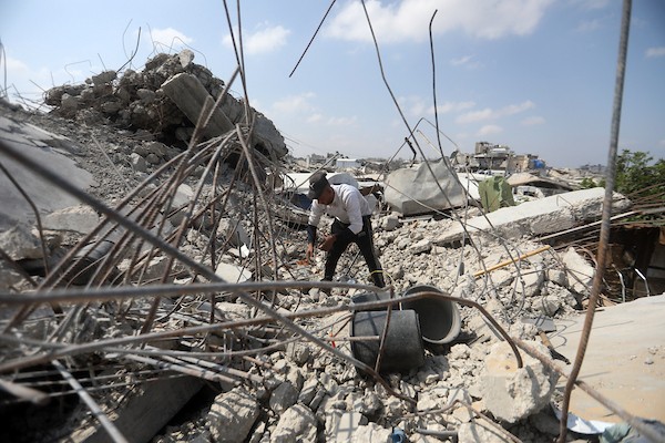 عمال فلسطينيون يستخرجون الحديد من أنقاض منازل مدمرة في حي التفاح بمدينة غزة لإعادة استخدامه في تدعيم خيام ومساكن مؤقتة للنازحين. (تصوير: بلال أسامة)