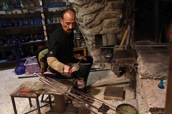 صانع الزجاج الفلسطيني يعقوب النتشة يقف بين منتجاته داخل مصنعه في الخليل، في 25 أغسطس/آب 2026، بعد استئناف عمله إثر توقف استمر ثلاث سنوات.(صورة: مأمون وزواز)
