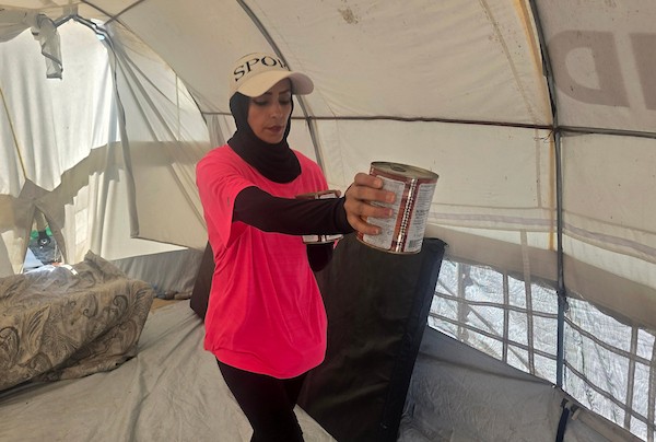 مدربة اللياقة البدنية إيمان المغير تستخدم علب طعام فارغة ومواد مهملة كأدوات رياضية خلال تدريبها داخل خيمتها في خان يونس.تصوير: طارق محمد