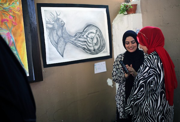 حضر فلسطينيون معرض ريشة السلام الذي ضمّ أعمالاً فنية ورسومات لشابات من مدينة غزة، وذلك في 30 أغسطس/آب 2026. تصوير: محمد صالحة
