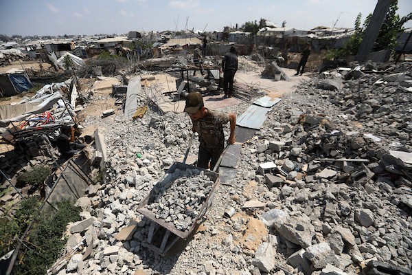 عمال فلسطينيون يستخرجون الحديد من أنقاض منازل مدمرة في حي التفاح بمدينة غزة لإعادة استخدامه في تدعيم خيام ومساكن مؤقتة للنازحين. (تصوير: بلال أسامة)