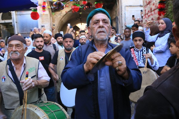 فلسطينيون بالزي التقليدي يؤدون أناشيد ومدائح دينية ويوزعون الحلوى في السوق المركزي بالبلدة القديمة في نابلس،خلال إحياء ذكرى المولد النبوي الشريف، في 25 أغسطس/آب 2026. (تصوير: محمد ناصر)