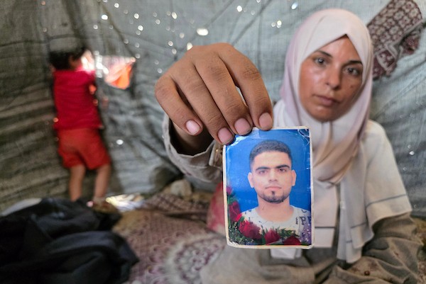 الفلسطينية فاطمة النجار تحمل صورة شقيقها محمد داخل خيمة للنازحين في خان يونس، جنوب قطاع غزة، في 30 أغسطس/آب 2026، بينما تواصل انتظار أي خبر عن مصيره في اليوم الدولي للمفقودين. تصوير: طارق محمد